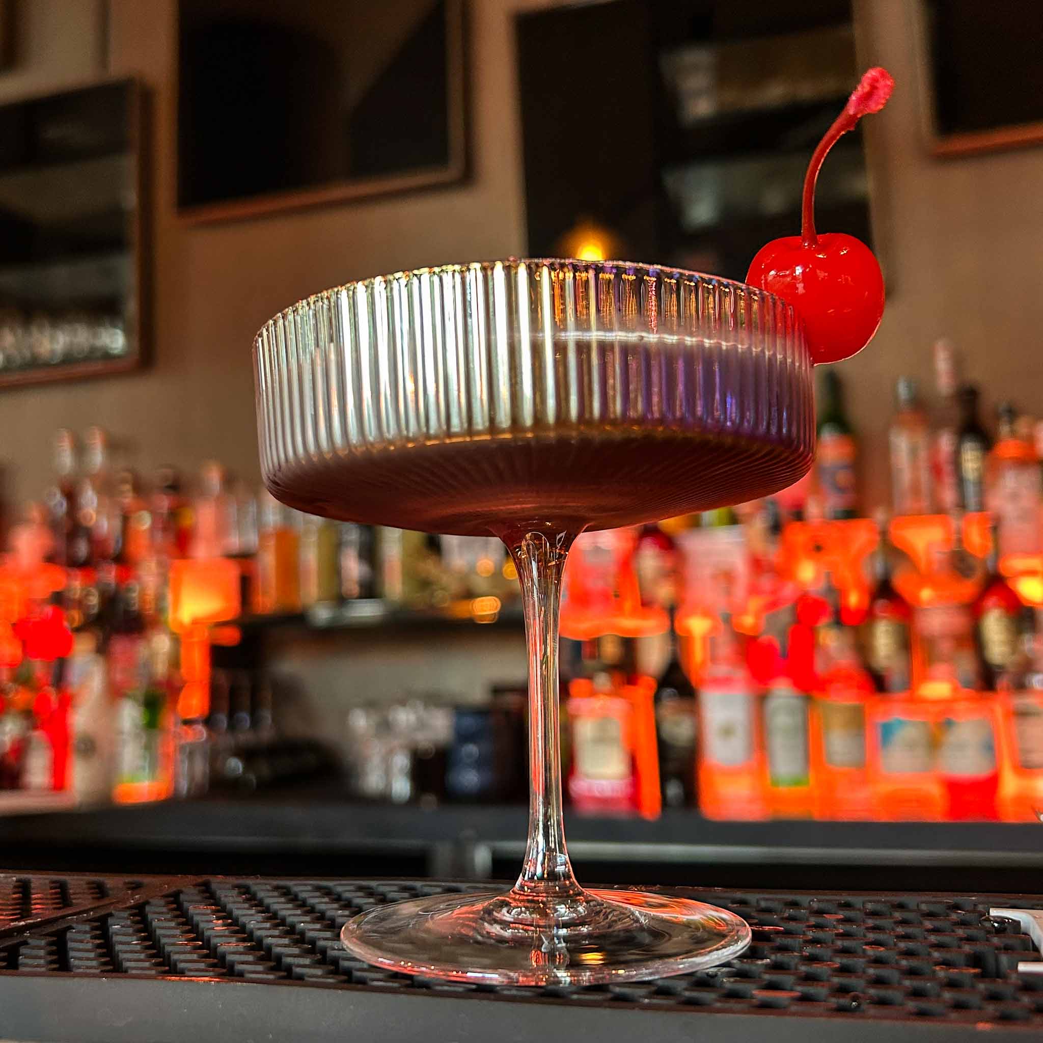 Manhattan cocktail recept met Rye Whiskey, zoete vermout en Angostura bitters, geserveerd in een vintage coupeglas met maraschino kers.