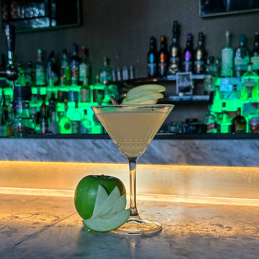 Cocktail recept: Sour Apple Martini. Appletini is een frisse, zure mix met vodka en groene appel, geserveerd met een simpele appelgarnish. 