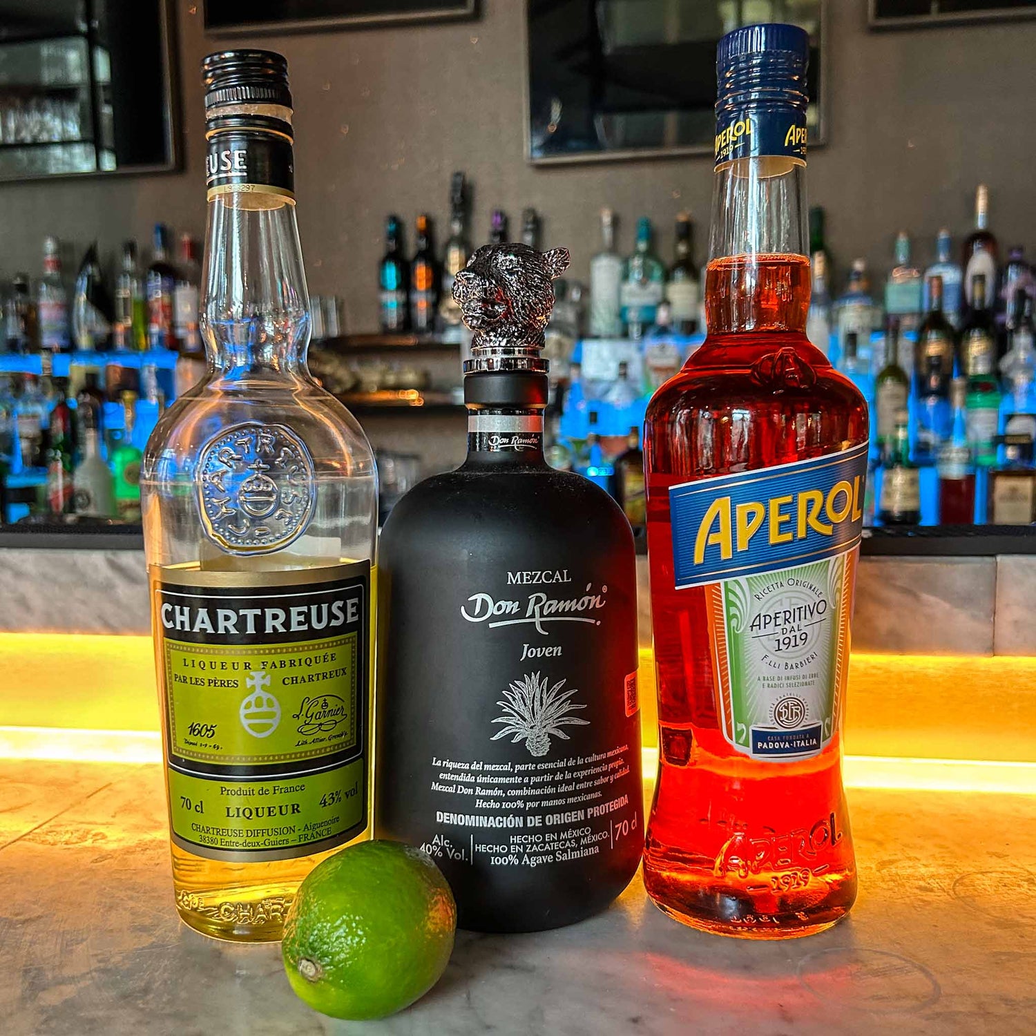 Naked & Famous cocktail in een gekoeld coupeglas, met rokerige mezcal, Aperol, gele Chartreuse en een schijfje limoen als garnish.