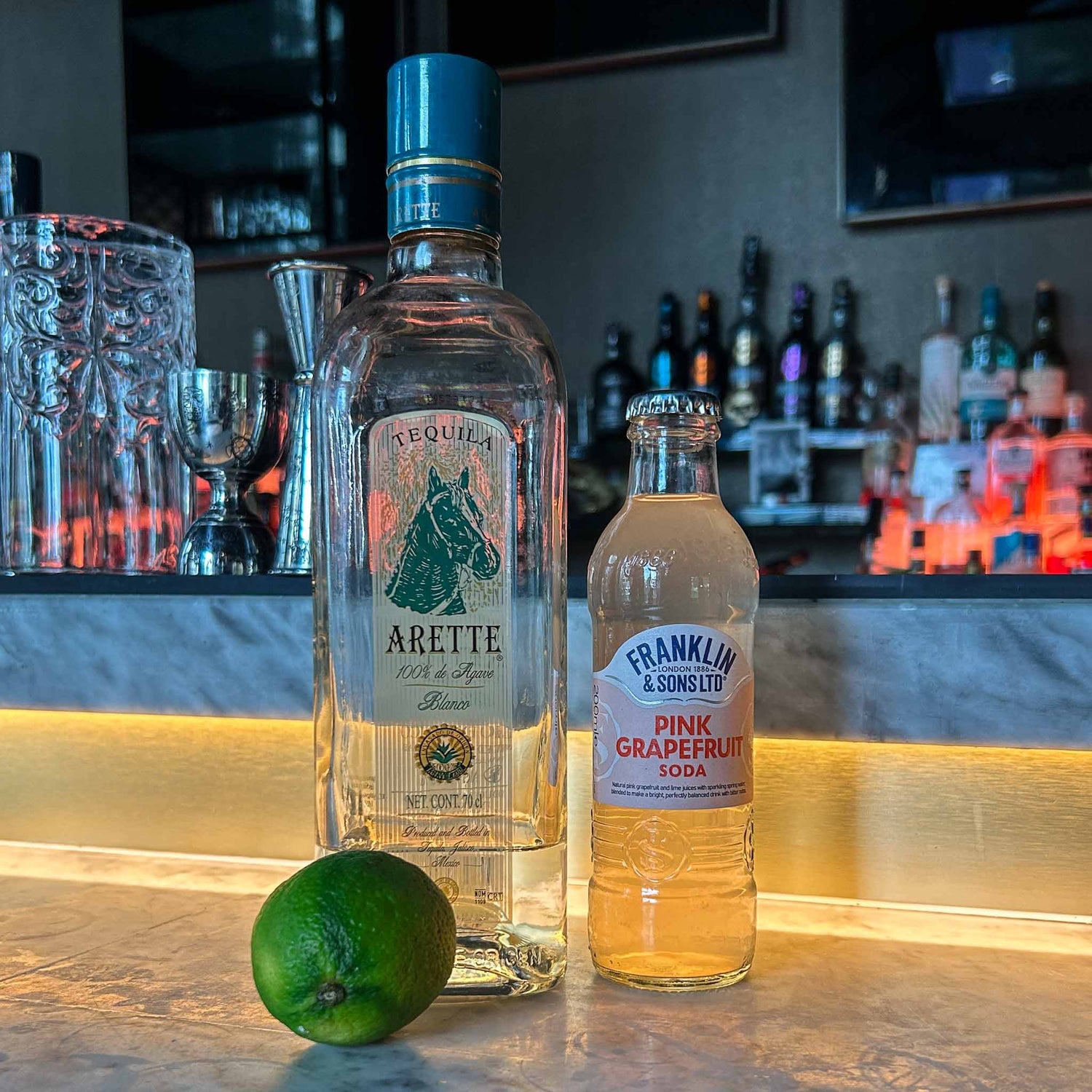 Cocktail recept: Paloma. Een frisse mix van tequila, limoen en grapefruit soda, geserveerd met ijs en een schijfje grapefruit.