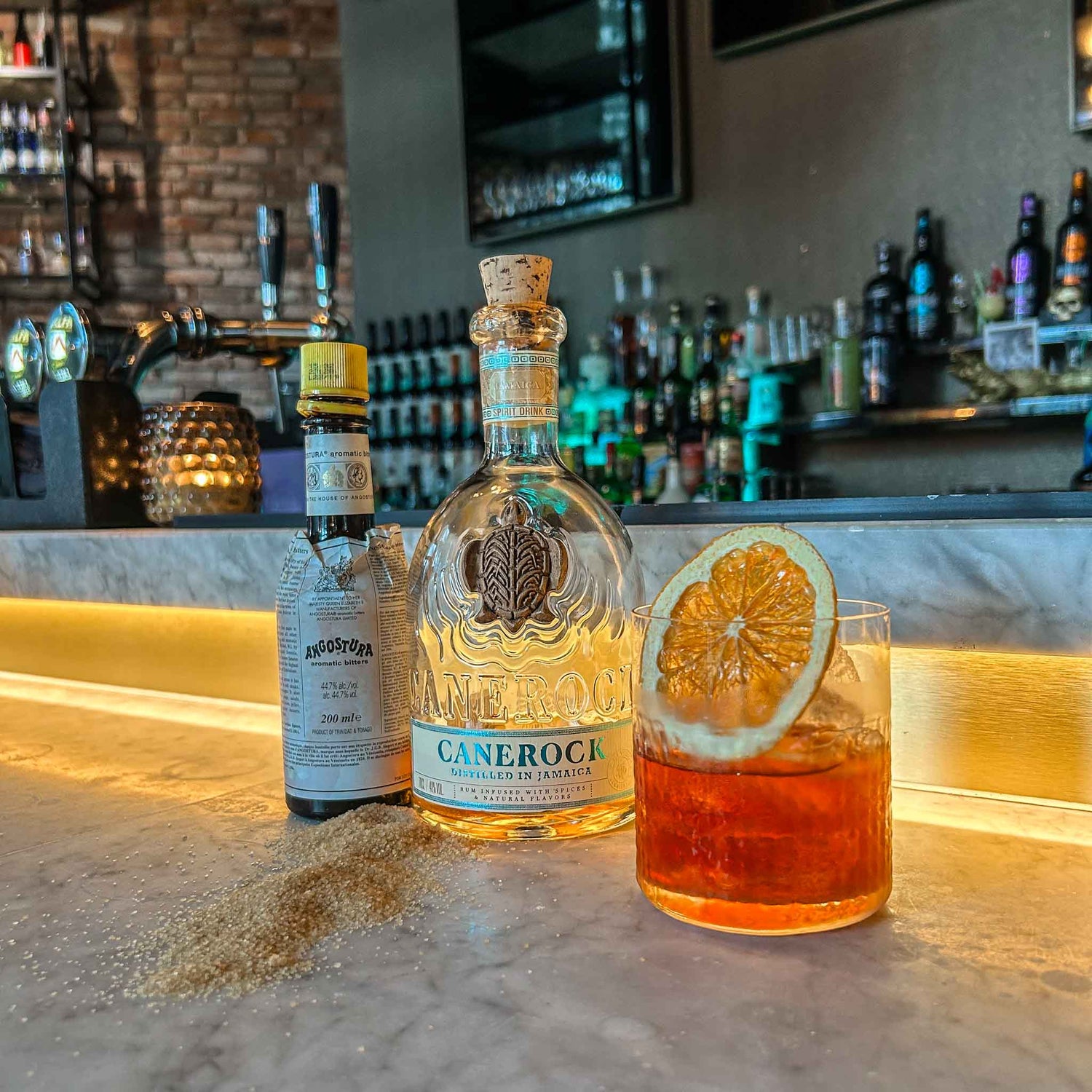 Rum Fashioned cocktail recept met gerijpte rum, rietsuiker en bitters in tumblerglas met sinaasappel. cocktail hotspots recept old fashioned.