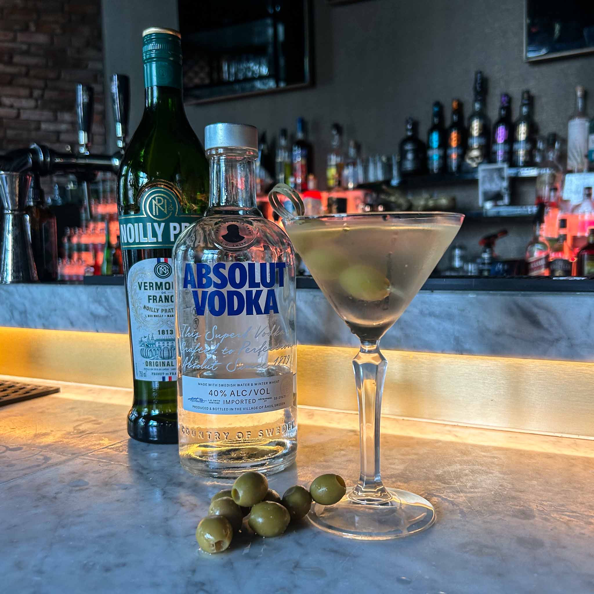 Recept Dirty Martini cocktail met vodka, droge vermouth en groene olijven, geserveerd in een gekoeld martiniglas.