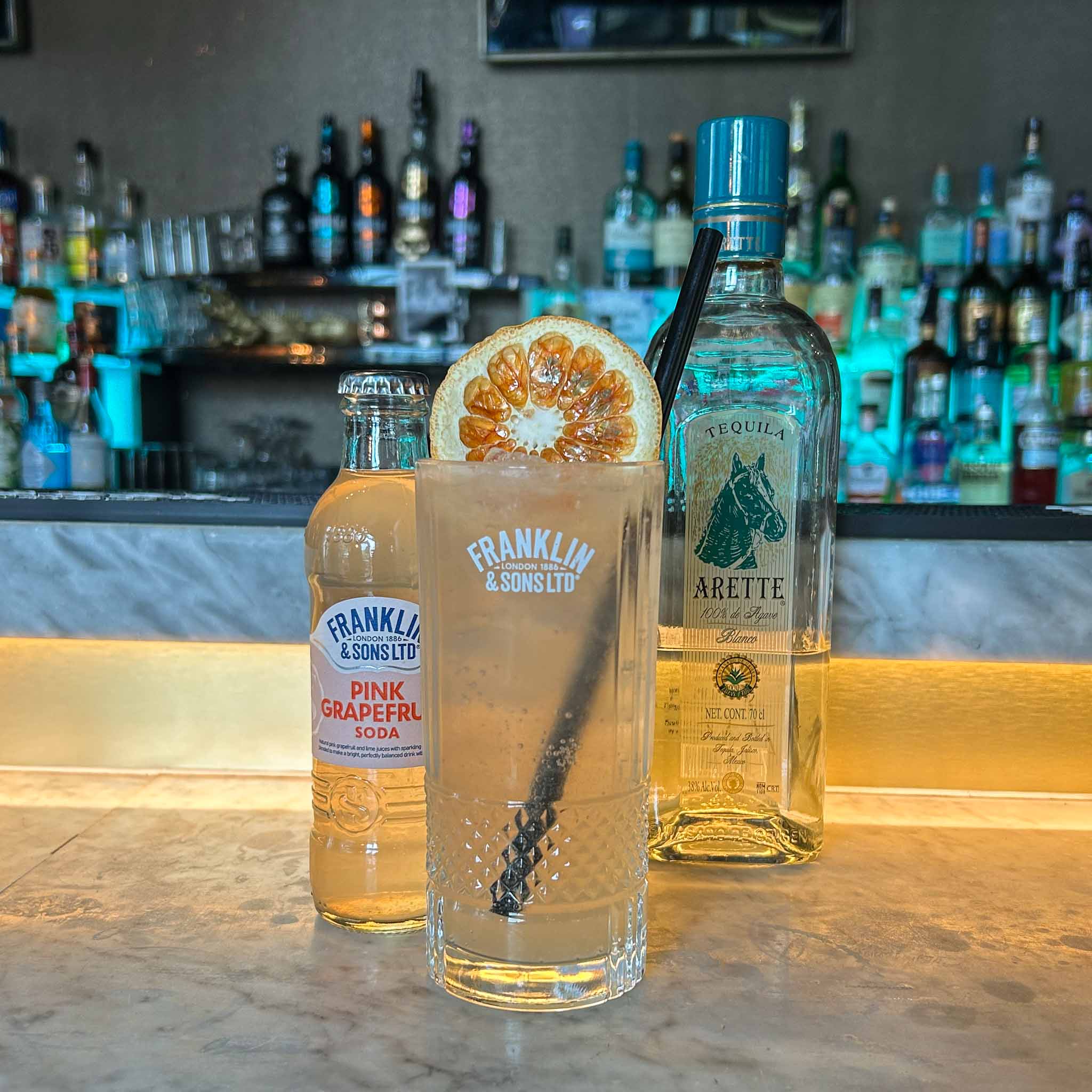 Cocktail recept: Paloma. Een frisse mix van tequila, limoen en grapefruit soda, geserveerd met ijs en een schijfje grapefruit.